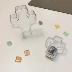 Clear plastic cross-shaped jewelry storage box showing open and closed positions for rings