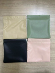 Detailed view of four colorful PU leather cosmetic bags with squeeze top closure on wood