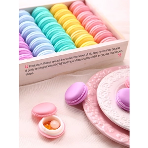 Detailed view of an open pink macaron storage case holding yellow medicine capsules