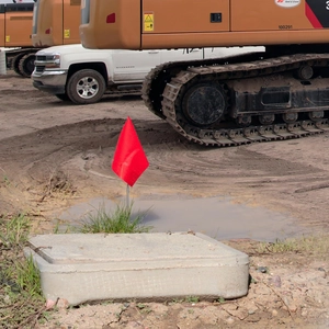 Close-up of a red triangular marking flag on a metal stake at a construction site