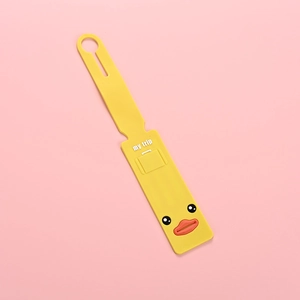 Detail of yellow PVC luggage tag with My Trip text and cute duck face on pink background