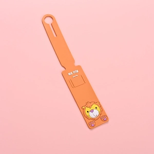 Macro shot of an orange PVC luggage tag with a lion cartoon and my trip text detail