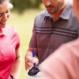 Close-up of golfer using black plastic alignment tool and blue marker to draw lines on golf ball