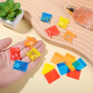 Mini colorful translucent self-sealing plastic jewelry bags shown in hand for scale
