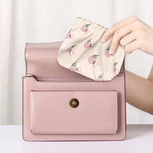Détail du mini sac de rangement motif pêche placé dans un sac à main en cuir rose