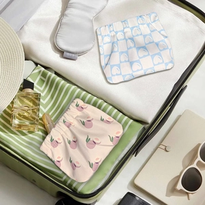 Détail de mini pochettes de voyage imperméables à motifs cœur et pêche dans une valise