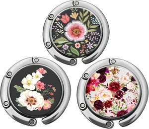 Dreiteiliges Set faltbarer Taschenhalter aus Metall mit eleganten Blumenmustern auf weißem Grund