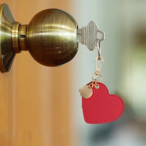 Red heart-shaped PU leather keychain with gold hardware on a door handle