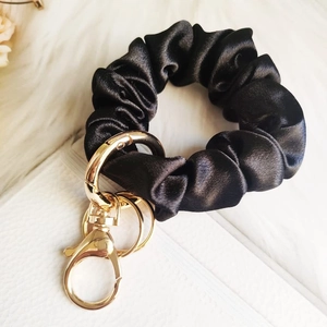 Close-up of black satin scrunchie keychain with elegant golden lobster clasp hardware