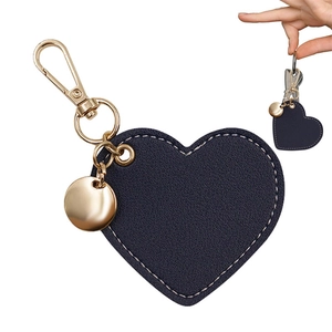 Detail of navy blue heart-shaped leather keychain with gold hardware and contrast stitching