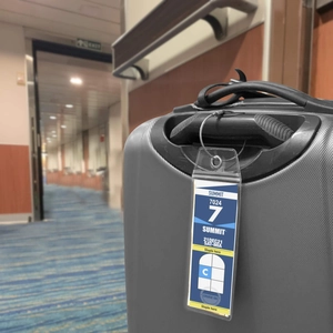 Vertical transparent PVC cruise luggage tag with stainless steel wire loop on a suitcase