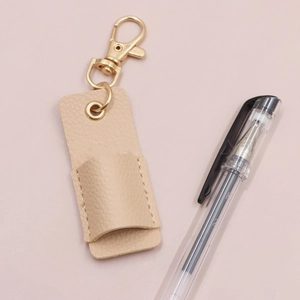 Close-up of beige pebble grain leather pen holder with golden metal swivel lobster clasp