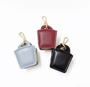 Three mini leather handbag charms in grey, burgundy, and black with golden metal hardware