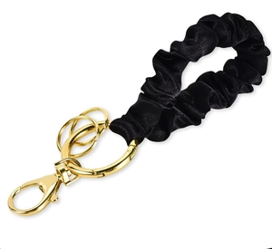 Detail of black pleated fabric wristlet keychain with polished gold metal hardware