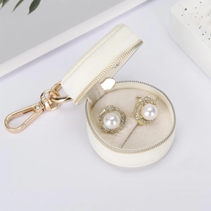 Close-up of pearl earrings inside a white woven mini jewelry box with a gold clasp