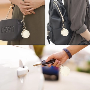 White leather mini jewelry pouch and AirTag holder attached to different bags as a charm