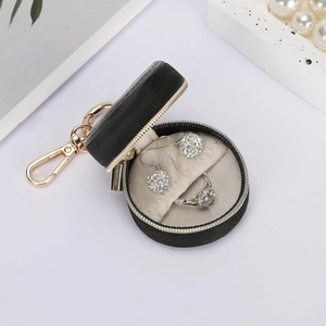 Close-up of a mini round jewelry box with gold zipper, keychain, and velvet interior lining