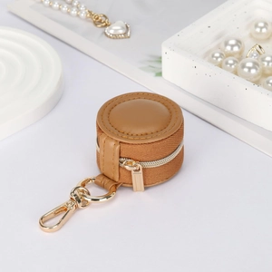 Detail of round mini jewelry case with brown leather lid, canvas side and gold zipper