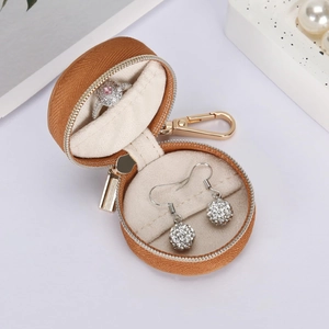 Close-up of portable round leather jewelry case with rings and gold zipper hook
