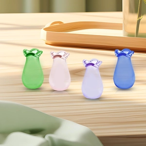 Set of four colorful droplet glass mini flower vases with elegant ruffled rims on wood