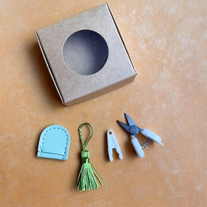 Flat lay of mini precision scissors set with leather sheath and decorative tassel
