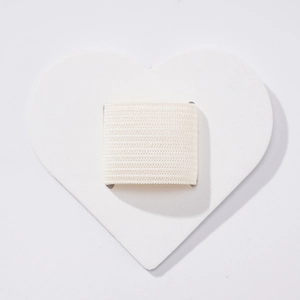 Macro detail of white heart-shaped PU leather pen holder with elastic loop for notebooks