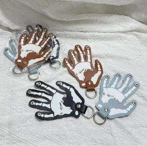 Detail of leather skeleton hand keychains with white bone prints and metal rivets