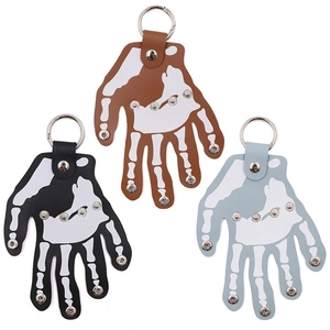 Three punk leather skull hand keychains in black, brown, and blue with metal rivets