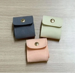 Close-up of microfiber jewelry pouches in grey green and pink with gold snap button