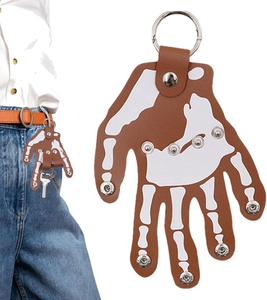 Detail of leather skeleton hand keychain with metal rivets on blue denim jeans