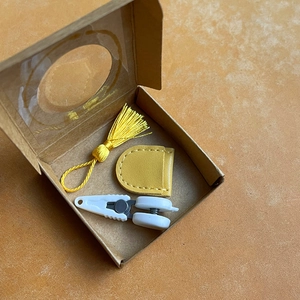 Close-up of mini sewing kit with yellow tassel, leather case, and white precision snips
