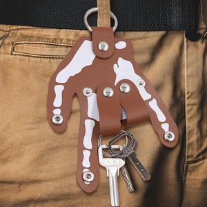 Brown leather hand-shaped keychain with skull bone print and metal rivets on a belt
