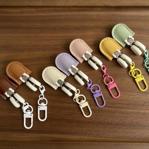Mini high precision scissors with colorful leather cases and metal hooks on wood background