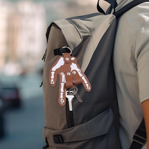 Detailed close-up of a brown leather skeletal hand keychain attached to a gray backpack