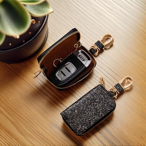 Sparkling black glitter leather car key case with gold hardware on a wooden background
