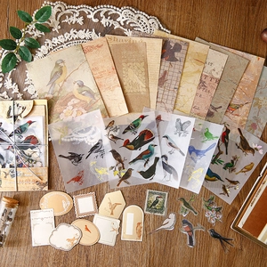 Retro bird theme scrapbooking kit with vintage paper and stickers on wooden surface