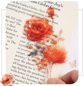 Detail of translucent orange watercolor rose stickers on a vintage book page