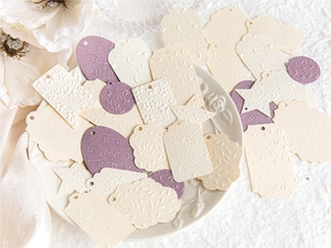 Detail of embossed vintage floral paper tags in various shapes on a ceramic tray