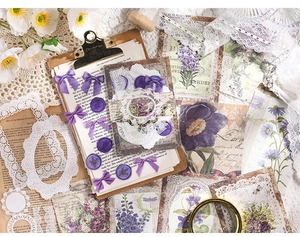 Detail of vintage scrapbooking kit featuring purple silk bows and floral lace papers