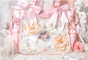 Close-up of pink satin ita bag with transparent window, lace, pearls and star charms