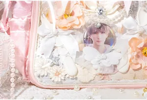 Detail of pink and white lace ita bag with satin bows, pearls and clear window