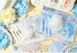 Macro detail of DIY lace plate decoration kit with blue cutlery and soft pom-poms