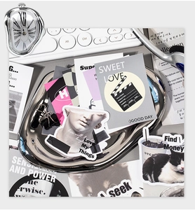 Macro shot of surreal melting mirror tray and artistic stickers on a minimalist desktop