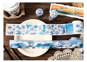 Macro view of ocean-themed washi tape rolls with watercolor sea waves and shell designs
