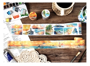 Detail of seaside watercolor washi tape showing waves and lighthouses on a wooden desk