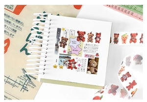 Close-up of teddy bear themed washi tape and stickers on a spiral notebook for DIY journaling
