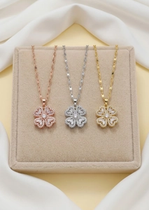 Detaillierte Ansicht von drei Kleeblatt-Anhängern in Roségold, Silber und Gold mit Zirkon