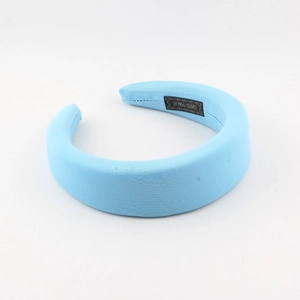 Detail view of handmade light blue padded headband with textured fabric and label