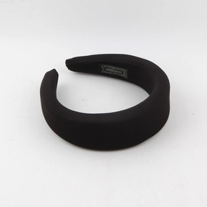 Detailed shot of thick black sponge headband featuring a woven HAND MADE interior label