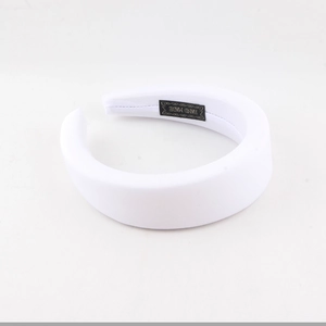 Close-up of white sponge padded headband featuring handmade woven label detail